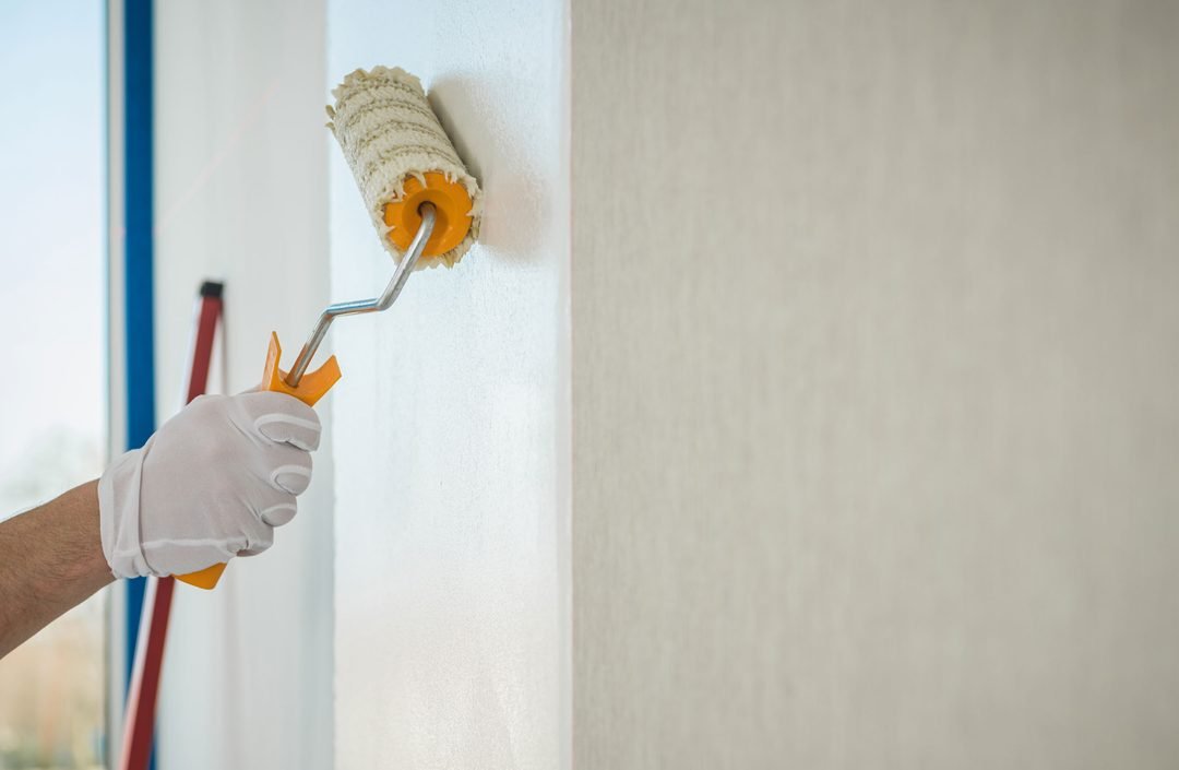 Kleister wird mit einer Rolle auf die Wand aufgetragen